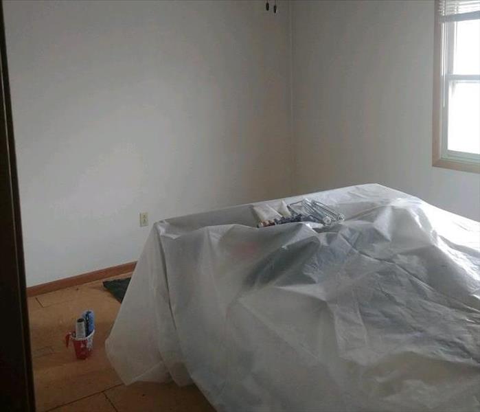 A bed properly wrapped and a fresh painted white room