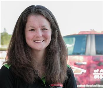 Female employee Carrie Bartmess in front of SERVPRO truck in background